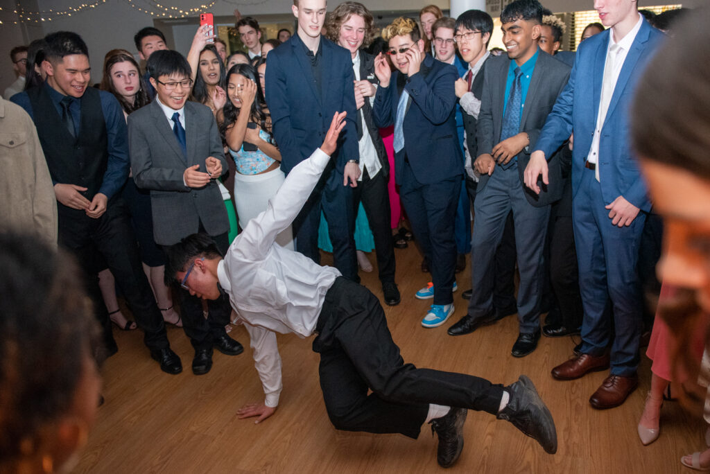 teens at formal dancing with one in center breakdancing