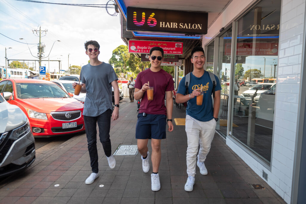 three teen boys walking down street with bubble tea in hand